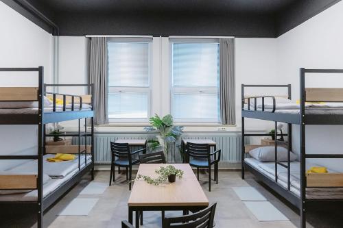 a dorm room with bunk beds and a table and chairs at Hostel Veronika Celje in Celje
