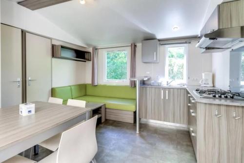 a kitchen with a green bench and a table at ZEcamping 4 pet friendly club enfant piscine bar et restanrant in La Bastide-de-Sérou