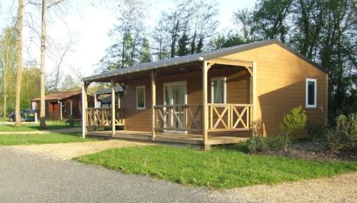 a large wooden cabin with a porch in the grass at ZEcamping 3 étoiles animaux acceptés espace aquatique in Moncontour-de-Poitou