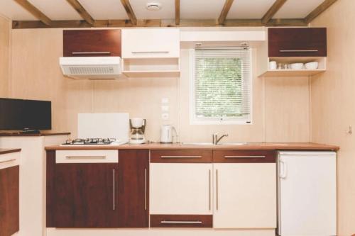 a kitchen with white and brown cabinets and a sink at ZEcamping 3 étoiles animaux acceptés espace aquatique in Moncontour-de-Poitou