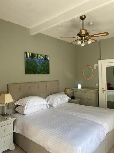 a bedroom with a white bed with a ceiling fan at Fernhill Hotel in Lyme Regis