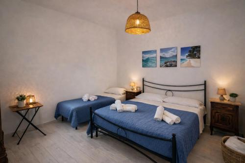 two beds in a bedroom with blue sheets at La riva in Noto Marina