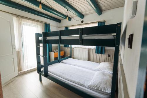 a bedroom with a bunk bed with white sheets at Cabana Vitus Panzió in Harghita-Băi