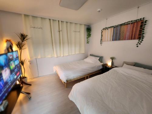 a bedroom with two beds and a flat screen tv at SweetJian SweetStay in Suwon