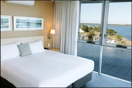a bedroom with a large bed and a large window at River's Edge Premium Retreat in Ballina