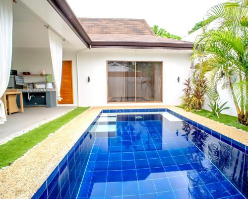 a blue tile swimming pool in front of a house at Bali Villas Panglao Bohol in Panglao Island