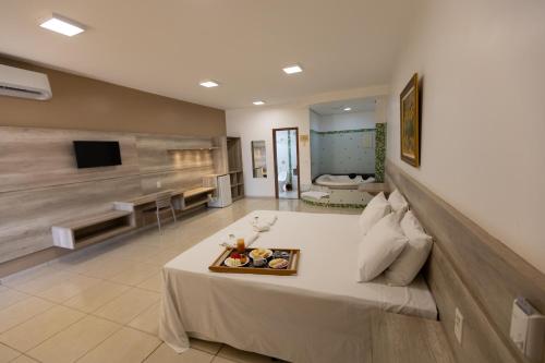 a large room with a bed with a tray of food on it at Aldeias Palace Hotel in Tucuma