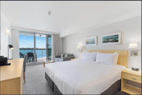 a hotel room with a bed and a desk and a view at Water Front Retreat Ballina in Ballina