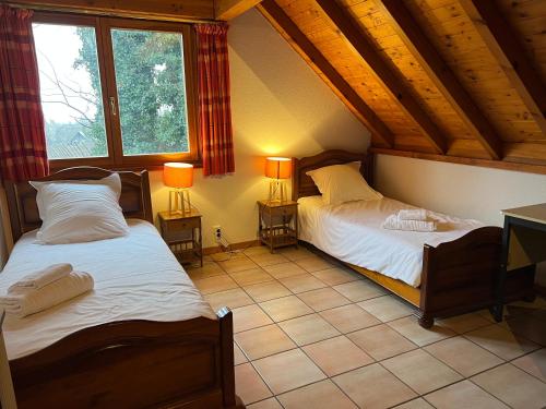 two beds in a room with two windows at La Canopée Alsacienne - Magnifique maison à Ribeauvillé in Ribeauvillé