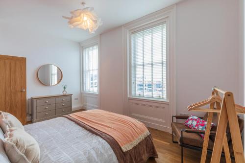 a bedroom with a bed and a chair and windows at Harbour-View Apartment Facing HMS Warrior in Portsmouth