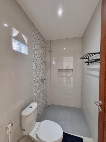 a white bathroom with a toilet and a shower at Paramulia house in Canggu