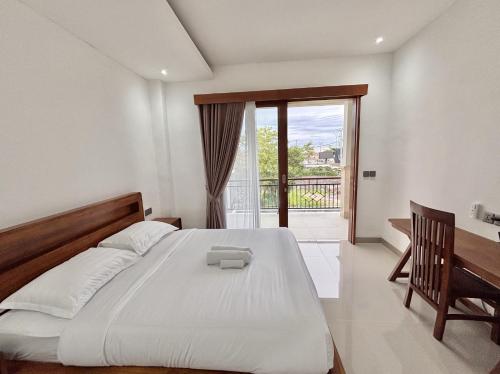 a bedroom with a bed and a desk and a window at Paramulia house in Canggu