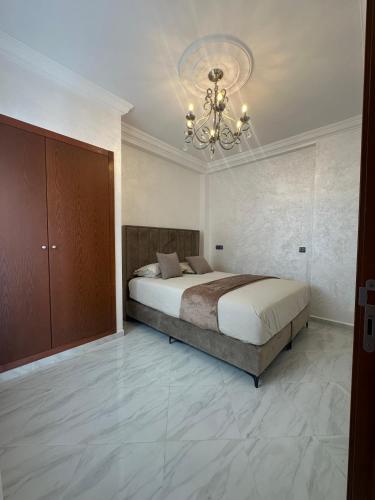 a bedroom with a large bed and a chandelier at Al Hoceima Mini Villa in Al Hoceïma