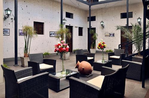 un patio con sillas, mesas y flores en un edificio en Hoteles Riviera Mansion en Arequipa
