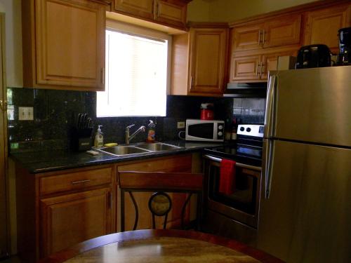 a kitchen with wooden cabinets and a stainless steel refrigerator at Pedro Villas in Tamuning