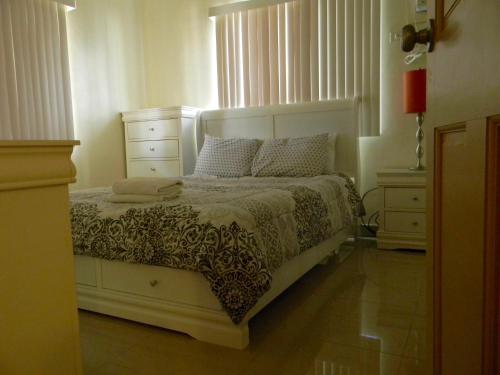 a bedroom with a white bed and two dressers at Pedro Villas in Tamuning