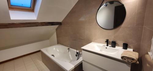 a bathroom with a sink and a tub and a mirror at Gîte des sources in Salbert