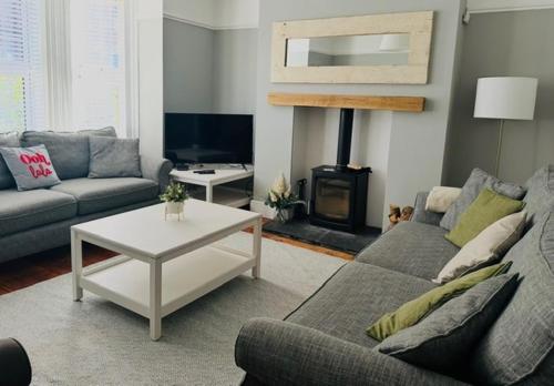 a living room with a couch and a fire place at Coast House Cromer - Sleeps 15, hot tub, sea views in Cromer