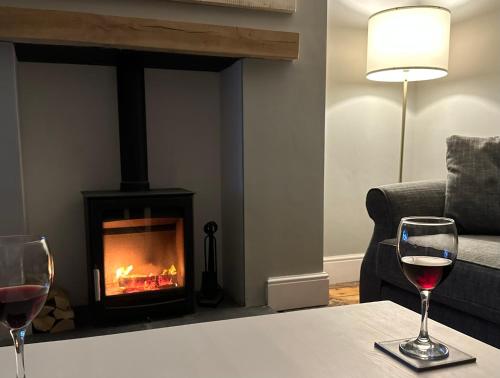 two glasses of wine on a table in front of a fireplace at Coast House Cromer - Sleeps 15, hot tub, sea views in Cromer