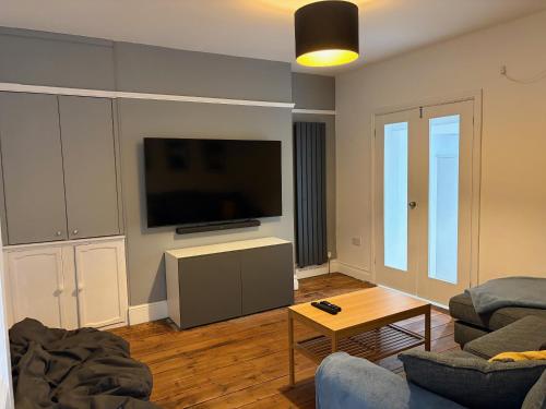 a living room with a couch and a flat screen tv at Coast House Cromer - Sleeps 15, hot tub, sea views in Cromer