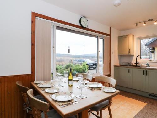 a dining room with a table and a clock on the wall at Alba Ben View in Spean Bridge