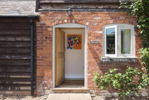 a brick house with a white door and a window at Stable Cottage at Hanley Mill in Tenbury
