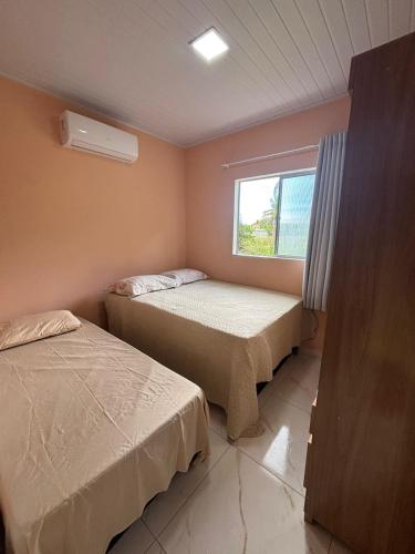 two beds in a small room with a window at pousada Bela Rosa in Santa Cruz Cabrália