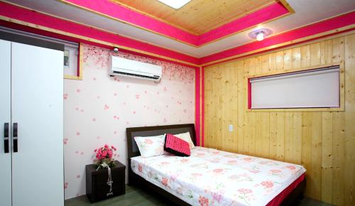 a bedroom with a bed in a room with pink walls at Pinky Marine Pension in Namhae
