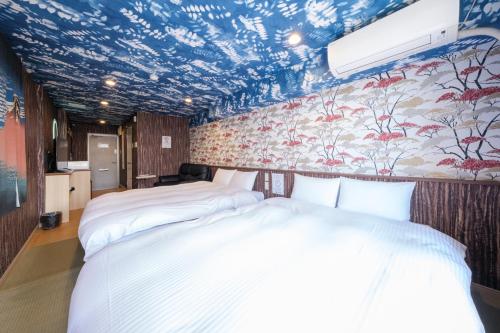 two beds in a room with a floral wallpaper at Tomaru House J in Chiba