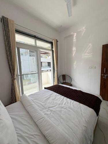 a bedroom with a large white bed with a window at Casa Aura Villa in Udaipur