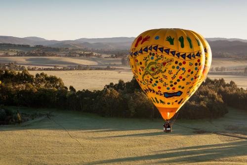 a yellow hot air balloon flying over a field at Yarra Valley Lodge in Wonga Park