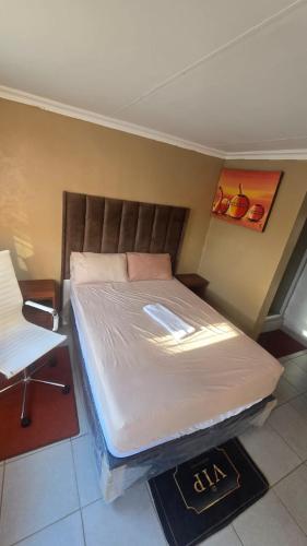 a bedroom with a bed and a chair at 6 Tiger guest house in Katlehong