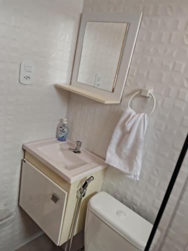 a bathroom with a sink and a toilet and a mirror at Aconchego da Alegria!!! in Porto Seguro