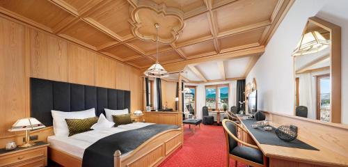a bedroom with a large bed and a desk at Panorama Vital Hotel Rimmele in Tirolo