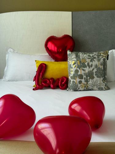 a bed with red heart shaped pillows on it at Hôtel Villa Berlioz in Lyon