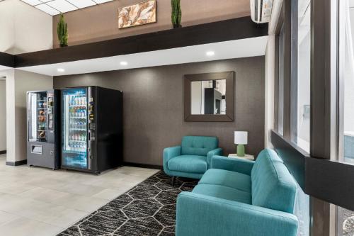 a lobby with two blue chairs and a soda machine at Cambridge Hotel - Kansas City in Kansas City