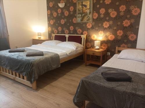 a bedroom with two beds and a wall with flowers at A-Piramida in Wrocław