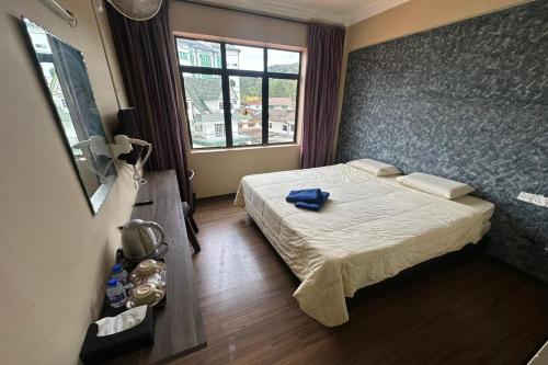 a hotel room with a bed and a window at Hotel Titiwangsa in Brinchang