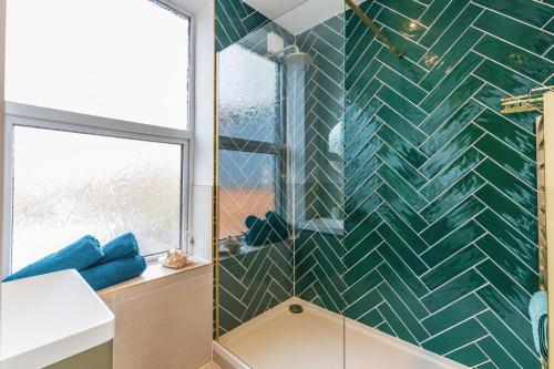 a bathroom with a green tiled wall at Spacious 2-Bed Flat with Panoramic Views in Portsmouth