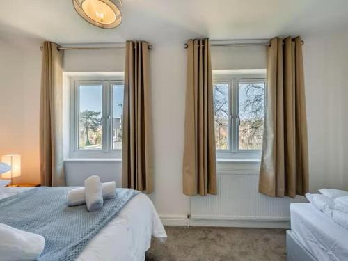 a bedroom with a bed and two windows at Beachside Bliss in Paignton