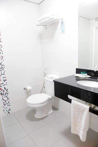 a white bathroom with a toilet and a sink at Hotel Premium Pirassununga in Pirassununga