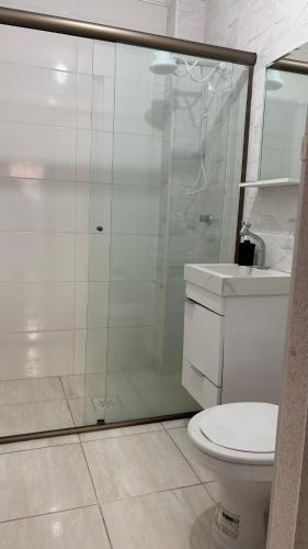 a bathroom with a shower and a toilet and a sink at Kit net a poucos passos do mar in São Vicente