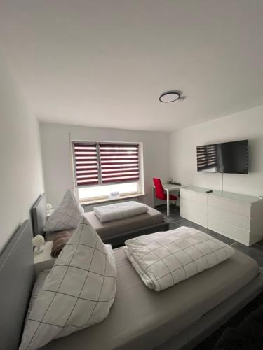 a bedroom with two beds and a desk and a television at Moderne 2 Zimmer Wohnung Küche und Bad im Zentrum in Merzig