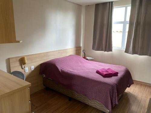 a bedroom with a bed with a purple blanket at Flats da Júnia 110 - funcional com ar, garagem, tv, microondas, frigobar e 14 km aeroporto in Lagoa Santa