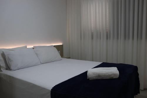 a bedroom with a white bed with a towel on it at Design e Amor no Centro in Palmas