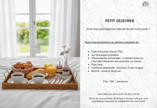 a tray of breakfast food on a bed with a menu at Charmant logement dans un écrin de verdure in Le Manoir