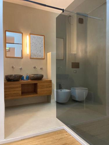 a bathroom with two sinks and a glass shower at Sa dommu de pedra in Santa Maria Navarrese