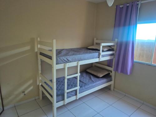 two bunk beds in a room with a window at Casa Recanto de Unamar in Cabo Frio