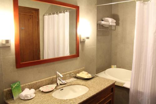 een badkamer met een wastafel, een bad en een spiegel bij Petro Hotel in Vung Tau