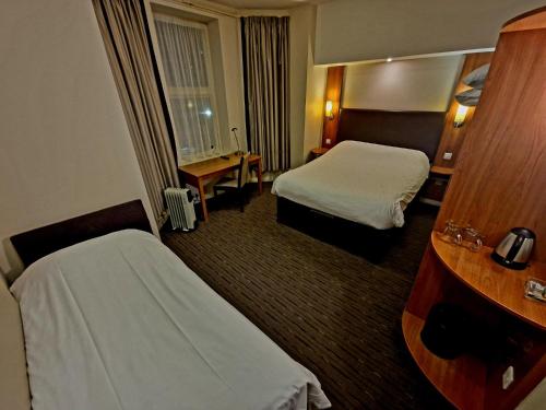 a hotel room with two beds and a desk at Charter Hotel Bournemouth in Bournemouth